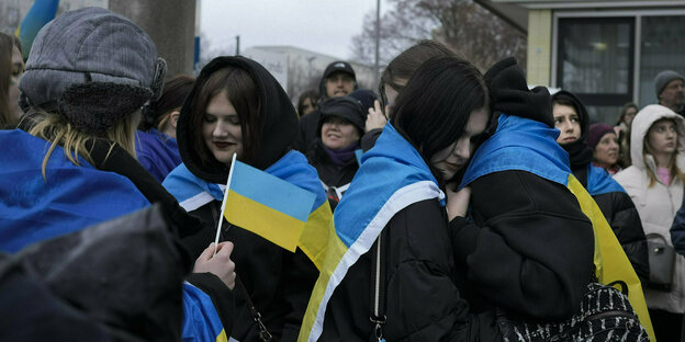 Junge Menschen mit Ukraineflaggen umarmen sich
