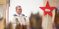 Bischof Bode bei einer Predigt, im Hintergrund ein Stern mit der Aufschrift "Freizeit"