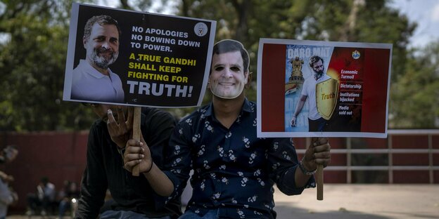 Fan von Rahul Gandhi mit einer Maske von ihm und zwei Schildern zur Unterstützung von ihm in der Hand in Delhi.
