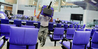 Ein Mann trägt einen der blauen Stühle aus dem Plenarsaal des Deutschen Bundestags