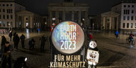 Ein Zeichen Earth Day vor dem unbeleuchteten Brandenburger Tor in der Nacht