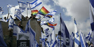 Menschen demonstrieren mit kleinen und großen Israel-Flaggen und vereinzelt mit Regenbogenflaggen