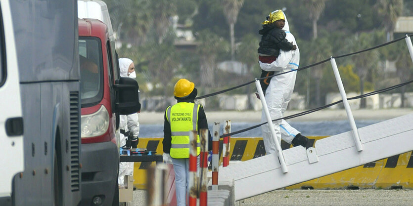 Schiff mit Geflüchteten in Reggio Calabria - ein kleines Kind wird von Bord getragen