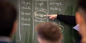 Das Wort "Religion" steht eingekreist auf einer Tafel.