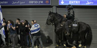 Ein Polizist sitzt auf einem Pferd neben Demonstrierenden