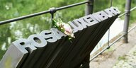Das Denkmal für Rosa Luxemburg - ihr Name in Bronze gegossen - mit einer Blume drapiert