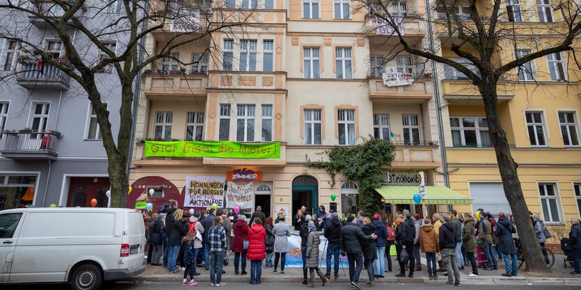 Menschen stehen vor einem haus, an dem Transparente hängen