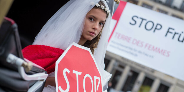 Ein Mädchen im Brautklied mit einem Stopschild aus Pappe