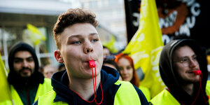 DemonstrantInnen in gelben Warnwesten, zum Teil mit Trillerpfeifen im Mund, protestieren vor einem Hotel