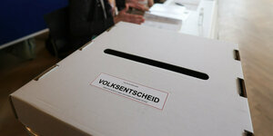 Bei dem Volksentscheid «Berlin 2030 Klimaneutral» am 26.3.23 sitzen Wahlhelfer vor einer Wahlurne in einem Wahllokal im Bildungs- und Kulturzentrum Peter Edel in Berlin-Weissensee.