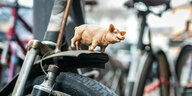 Ein kleines Schwein aus Plastik ist auf das vordere Schutzblech eines geparkten Fahrrades geschraubt