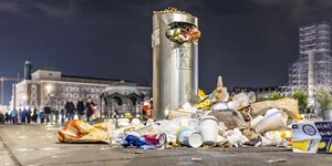 Überfüllter Mülleimer mit weiterm Müll drumherum