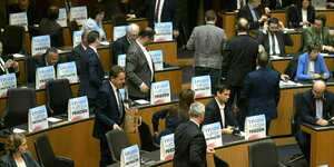 Im östereichischen Parlament stehen Abgeordnete der FPÖ vor ihren Plätzen, auf denen sind Aufsteller verteilt auf denen steht: Platz für Frieden, Platz für Neutralität