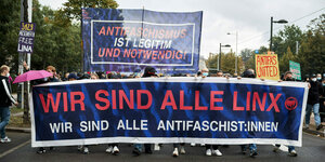 Das Bild zeigt eine Demo, auf der zwei Transparente getragen werden. Auf dem einen steht "Antifaschismus ist legitim und notwendig", auf dem anderen steht "Wir sinda lle Linx Wir sind alle Antifaschist:innen"