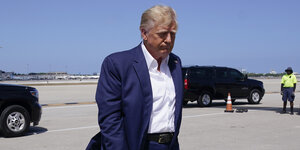 Trump mit gesenktem Kopf auf einem Flugplatz, seitlich fotografiert