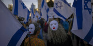Demonstranten tragen Masken und schwenken israelische Fahnen
