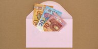 Euroscheine in einem rosafarbenen Briefumschlag