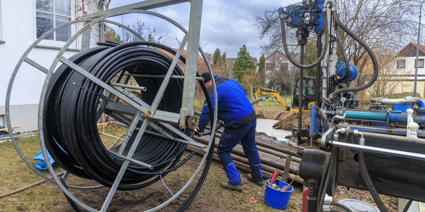 Dicke Kabel auf einer Rolle so hoch wie ein Mensch, daneben Arbeiter und weitere Geräte