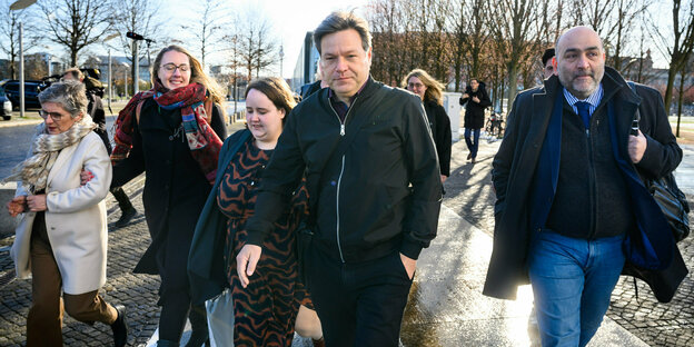 Grüne Abgeordnete, darunter Ricarda Lang und Robert Habeck, laufen draußen in Winterjacke herum