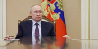 Putin, an einem Tisch sitzend