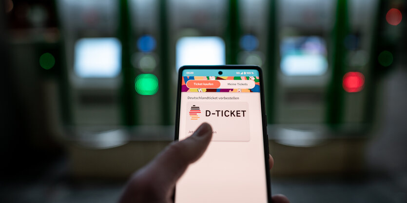 Ein Mann hält ein Smartphone mit der App, in der das D-Ticket gekauft werden kann