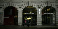 Eine Frau mit gelbem Regenschirm geht an einer Filiale der Schweizer bank Credit Suisse vorbei