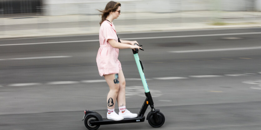 Eine Frau in rosa Kleidung fährt auf einem Elektroscooter