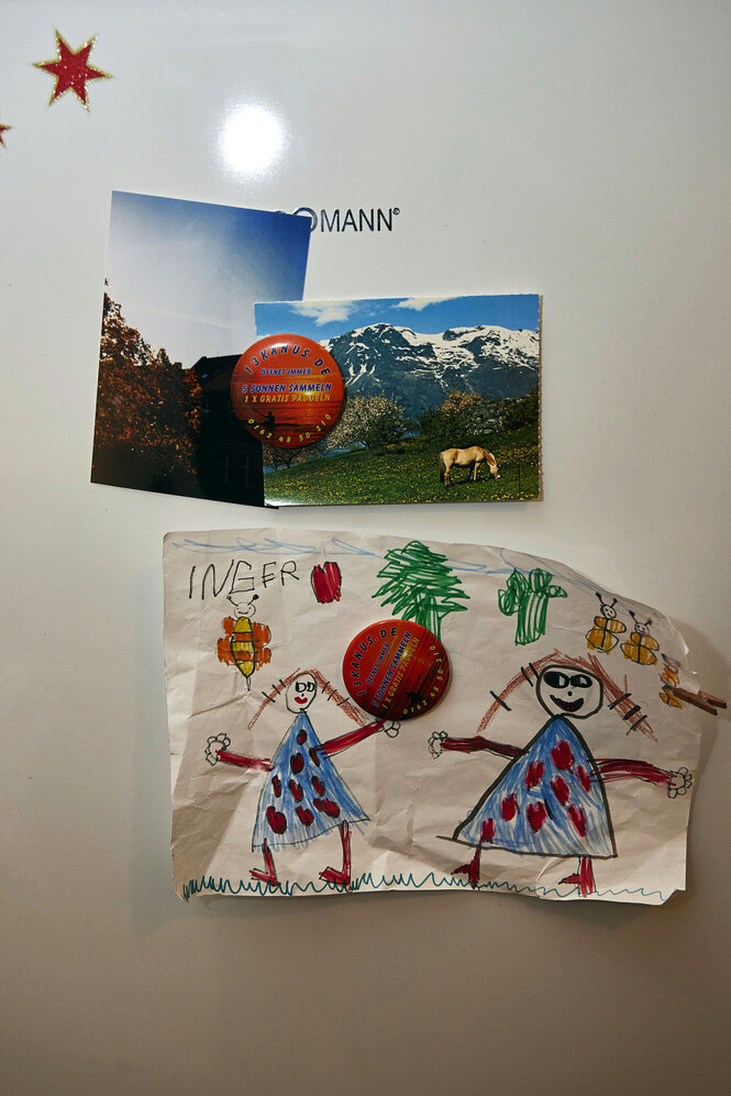 An der Wand hängen zwei Postkarten und eine Kinderzeichnung