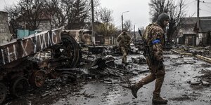 Zwei ukrainische Soldaten auf einer völlig zerstörten Straße im Butscha