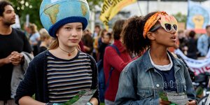 Schülerinnen von Fridays for Future bei einer Demo in Berlin, ein Mädchen hat eine Weltkugel auf dem kopf