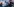 Ein Polizist mit Mundschutzmaske, im Hintergrund ein Transparent und viele Menschen