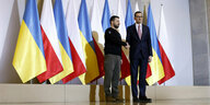 Selenski und Mateusz Morawiecki geben sich die Hand vor Fahnen ihrer Länder