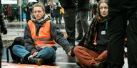 Aktivistinnen blockieren sitzend eine Straße in Berlin