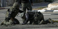 Behelmte israelische Polizisten in Kampfanzügen entfernen auf einer Straße in Schlomi Reste eine abgefangenen Rakete, die aus dem Libanon abgefeuert worden war