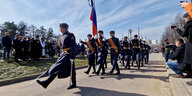 Russische Militärangehörige marschieren auf einem Friedhofsweg