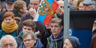 Zu sehen sind mehrere Demonstranten, von denen einer eine Russland-Fahne hält