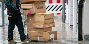 Ein Mann schiebt einen riesigen Stapel Postpakete vor sich her