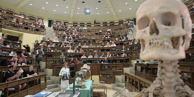 Hörsaal mit Studierenden im Vordergrund ein menschliches Skelett