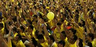 Eine Demonstration, Menschen heben die Arme, sie tragen Gelb