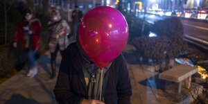 Eine Frau versteckt hinter einem Ballon ihren Kopf