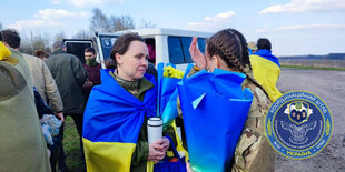 Frauen in ukrainische Fahnen gehüllt an einer Landstraße