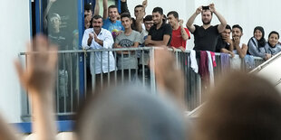 Demonstranten vor der Flüchtlingsunterkunft in Heidenau. Vom Balkon winken einige Flüchtlinge zurück.