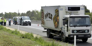 Der Lastwagen, in dem tote Geflüchtete gefunden worden sind, steht am Autobahnrand. Im Hintergrund Polizei.