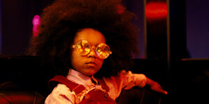 Ein etwa zehnjähriges Mädchen mit Sonnenbrille und Afrofrisur