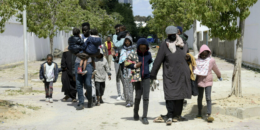 Erwachsene und Kinder mit Gepäck auf einer Straße