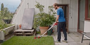 Ein Mann auf einem Balkon pflegt seinen Rasen