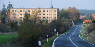 Ruine eines DDR-Plattenbaus, eine Straße, im Hintergrund ein Kirchturm.