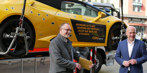 Falko Liecke und Kai Wegner bei einer CDU-Aktion vor einem gelben Sportauto, das abgeschleppt wird