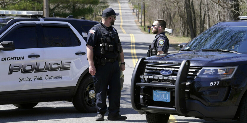 US-Polizisten hinter ihren Autos auf einer nicht befahrenen Landstraße