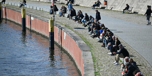 Menschen sitzen in der Sonne am Spreeufer